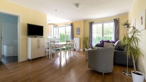 Un grand espace de vie comprenant une table à manger, un canapé et un téléviseur.