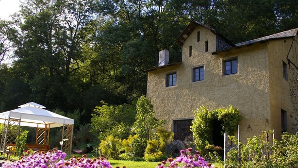 A two-story stone building with a garden in front.