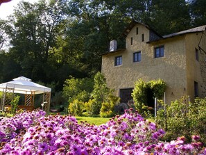 Un bâtiment en pierre de deux étages, avec un jardin à l’avant.
