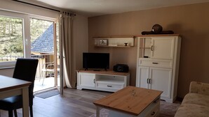 A living room with a dining area, a TV, and a radio on a wooden cabinet.