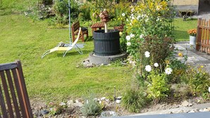 A garden with a wooden bench, a table, and a decorative fountain.