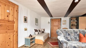 A cozy room with a bed, a sofa, wooden walls, a bookshelf, and a small table. - Sleep Under a Thatched Roof - Apartment in Ahlbeck near Haff (Ahlbeck)