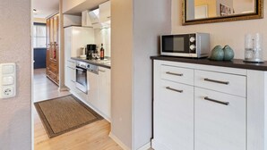 A modern kitchen with white cabinetry, a microwave, and a coffee maker on the counter. - Grosszugiges Apartment in Boltenhagen am Meer (Boltenhagen)