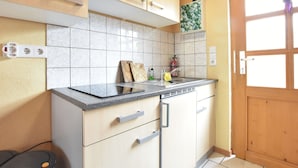A compact kitchen with light wood cabinets, a granite countertop, and a built-in dishwasher. - Holiday Home in Am Salzhaff (Am Salzhaff)
