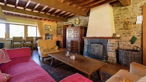 A cozy living room with a fireplace, wooden beams, stone walls, and comfortable seating. - Cozy Holiday House near La Roche (Rendeux)