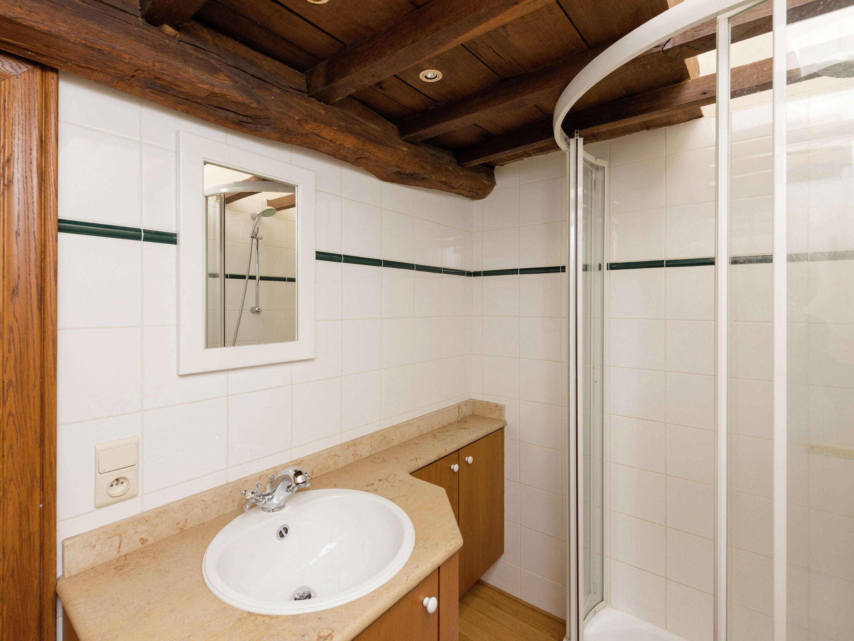 A bathroom with a sink, mirror, and shower.