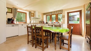 A spacious kitchen with a dining table, wooden chairs, and a green tablecloth. - Cozy Holiday House near La Roche (Rendeux)