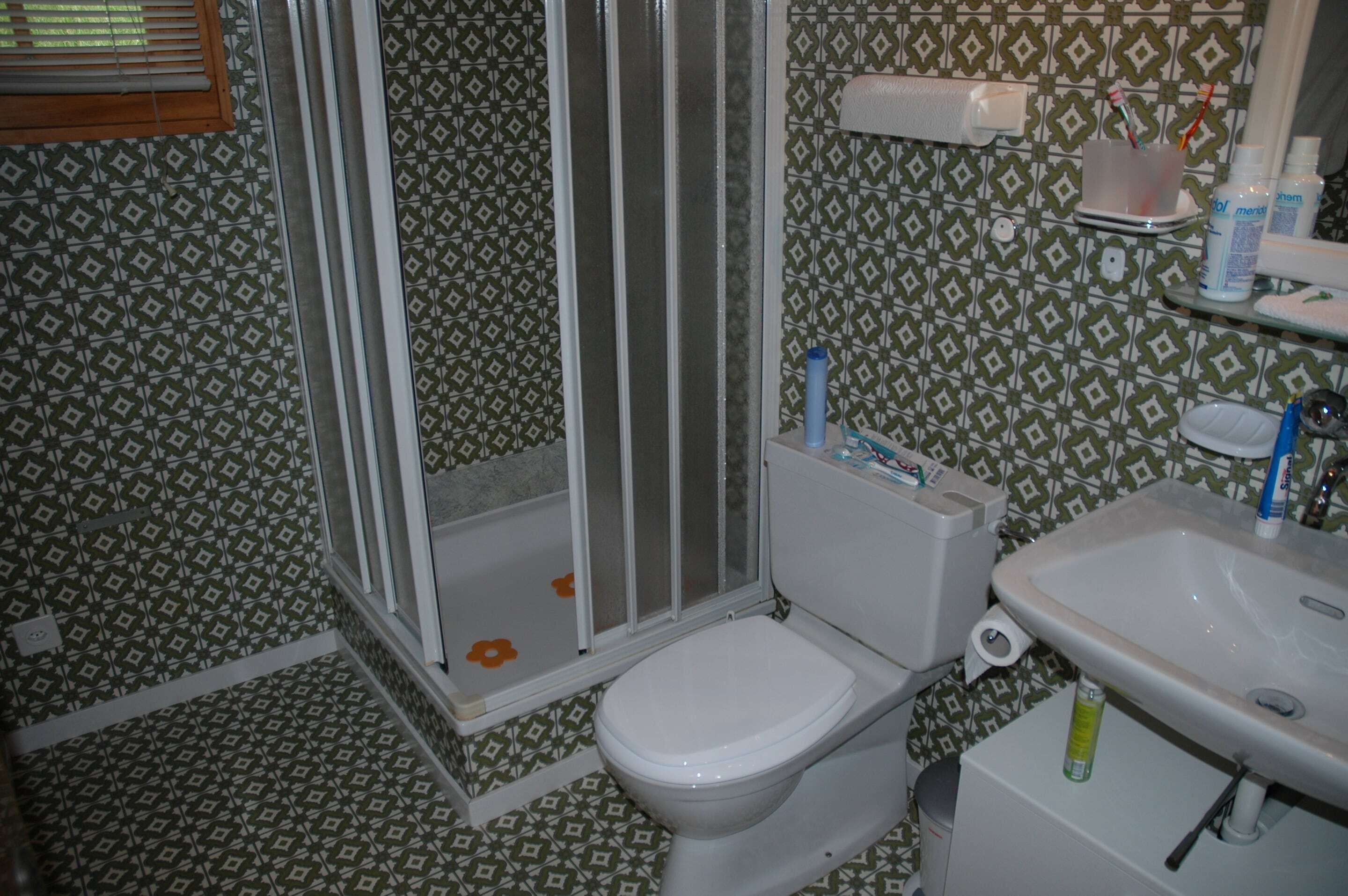 Un bagno con piastrelle decorate, un WC, un lavandino e un box doccia.