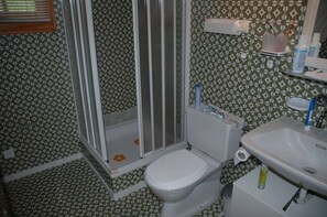 Casa de banho com azulejos estampados, sanita, lavatório e cabine de duche.