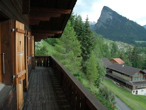 A wooden balcony with a view of a mountain and a village. - Detached Chalet With View of the Alps, Large Terrace and Veranda (Diemtigen)