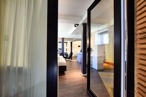 Quarto de hotel moderno com uma grande porta de vidro deslizante que dá para uma área de estar ampla.
