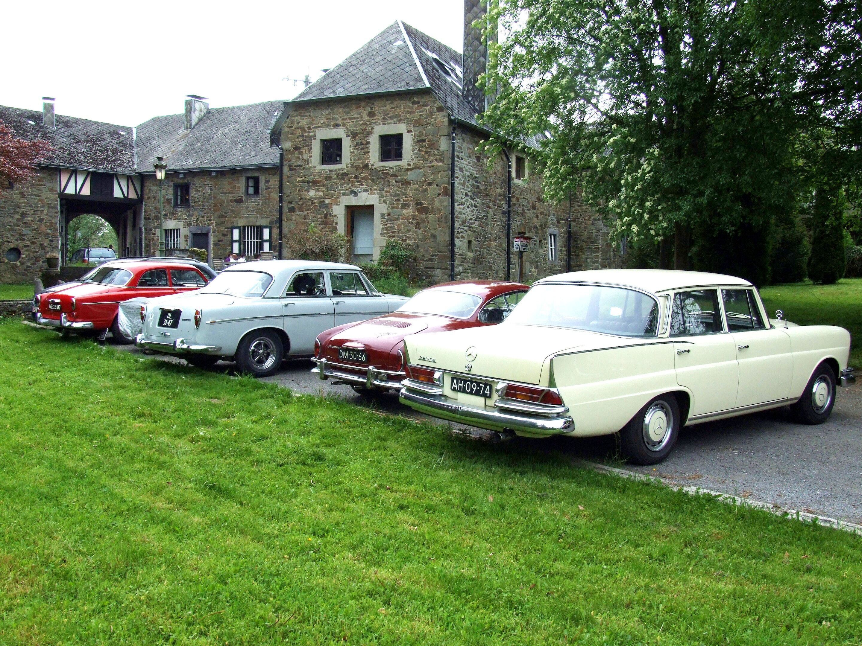 Una hilera de coches antiguos estacionados frente a un edificio de piedra con arquitectura tradicional.