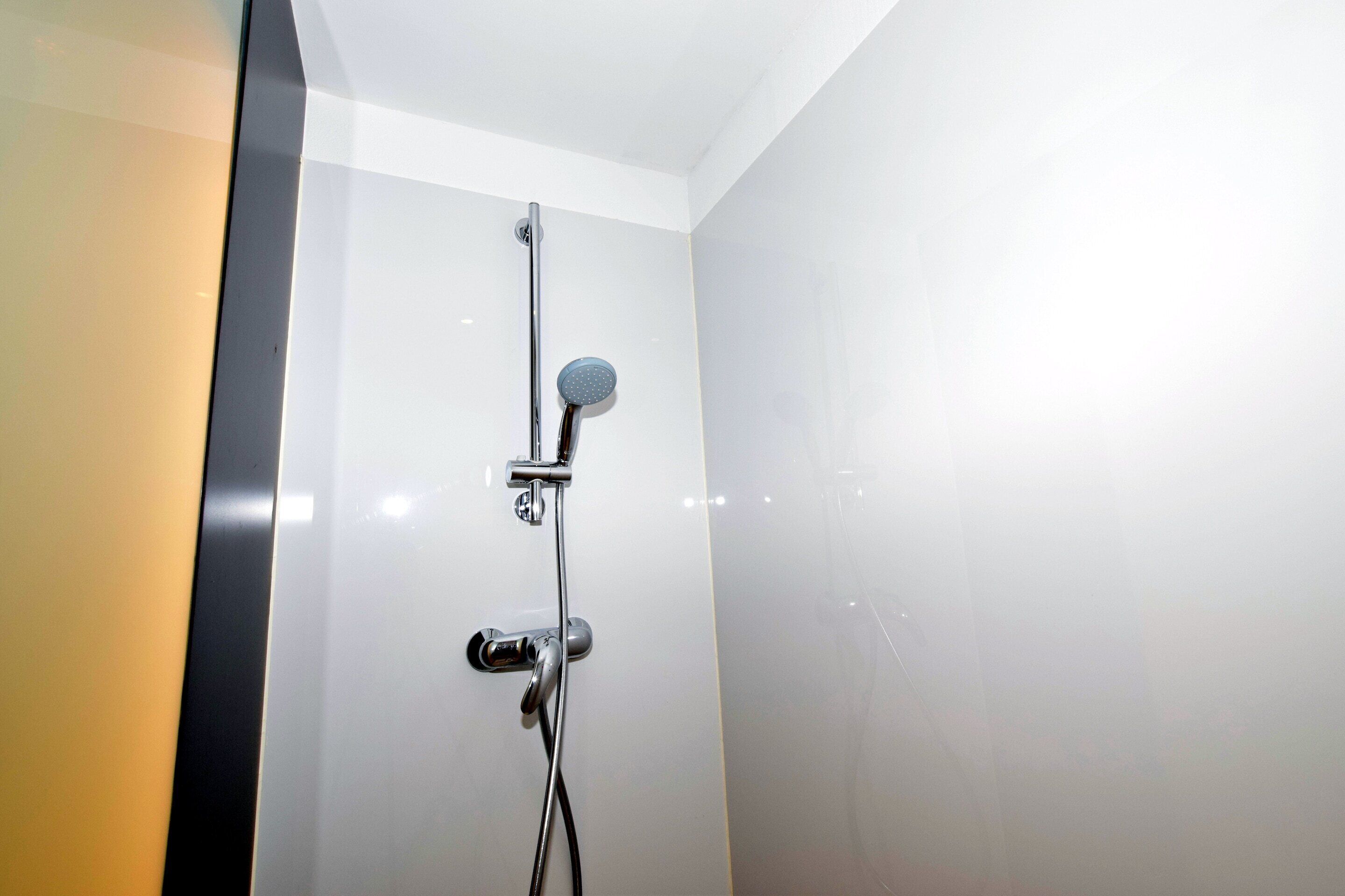 Une douche moderne dotée d’un pommeau de douche à main et d’un robinet mural.