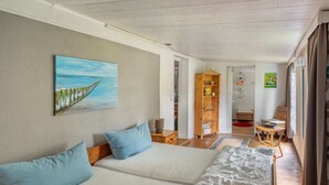 A room with two beds, a wooden bookshelf, a painting, and a view of a garden through a window. - Quaint Holiday Home near Forest in Stuer (Stuer)