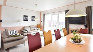 A modern living room with a sofa, chairs, a dining table, and a TV. - Pleasant Holiday Home in Malchow near Beach (Insel Poel)