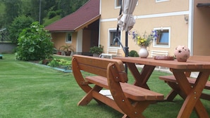 Una mesa de picnic de madera con bancos, una planta en maceta y una esfera decorativa sobre la mesa.
