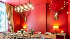 A dining area with a wooden table, chairs, and a chandelier. - Villa in Former School (Heers)