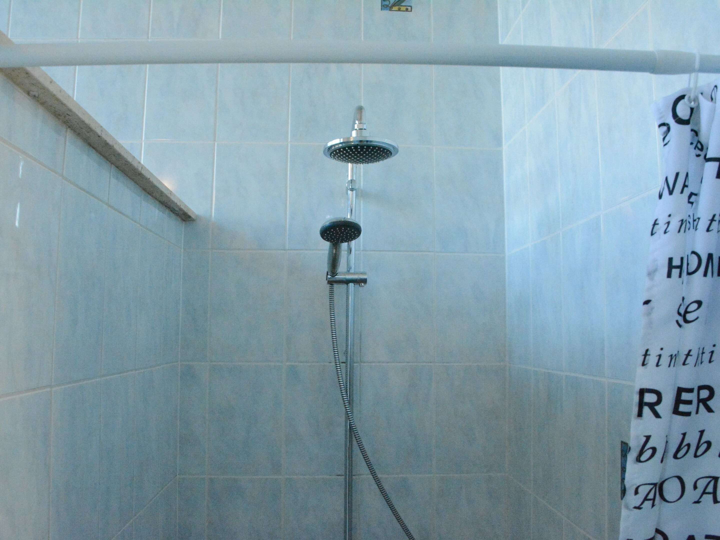 A shower area with a tiled wall and a showerhead.