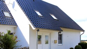 A two-story house with a steeply pitched roof, a front door, and a small porch. - Flat on the Island of Poel With Sauna (Insel Poel)