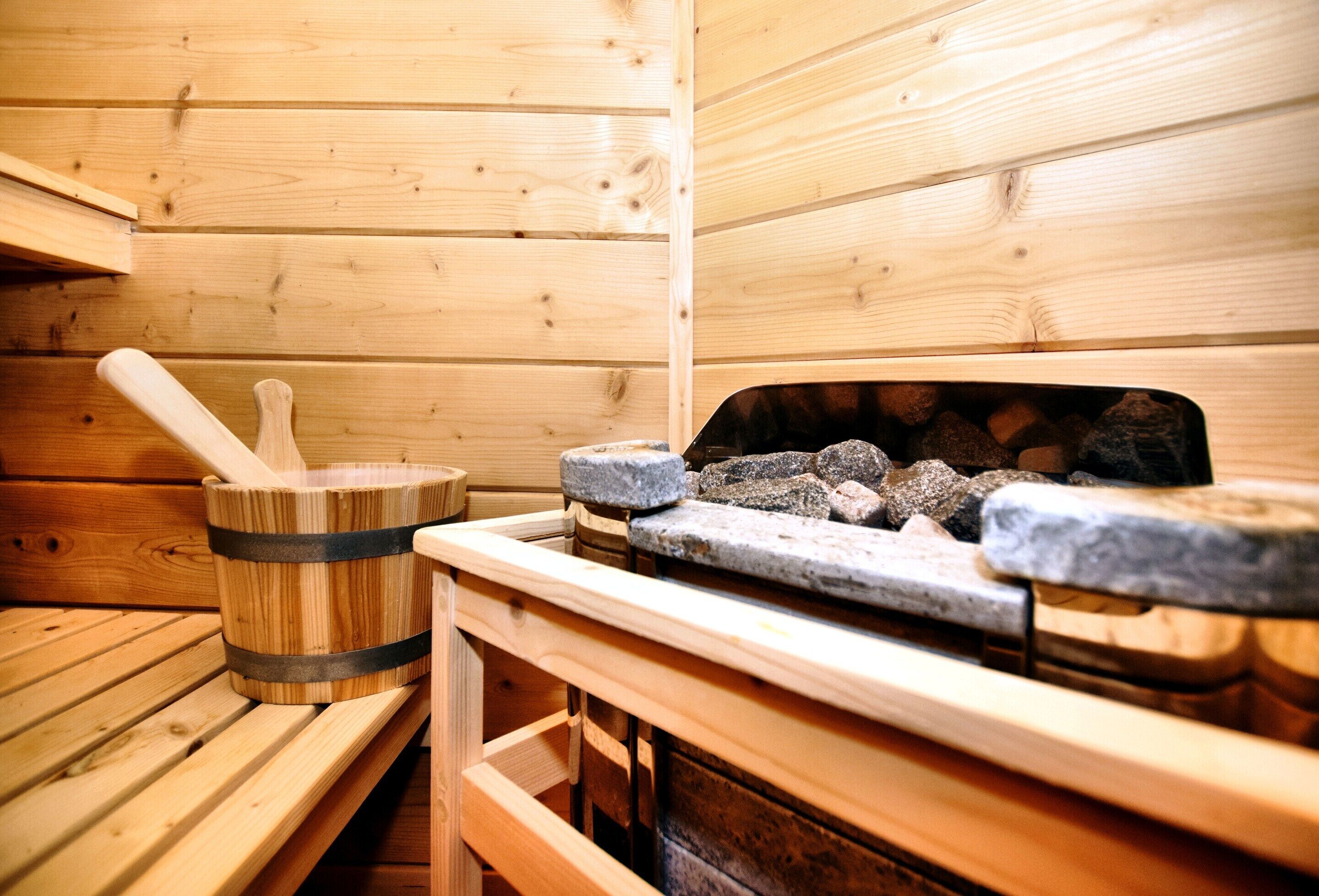 A sauna with wooden benches, a stone bench, and a stone heater with rocks.