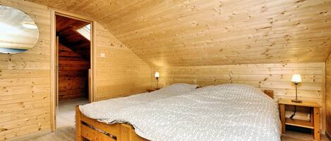 A wooden cabin bedroom with a bed, a nightstand, and a lamp.