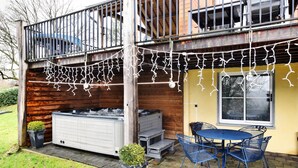 Un espace patio doté d’un jacuzzi, de sièges d’extérieur et de guirlandes lumineuses.