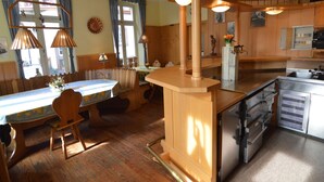 A kitchen with wooden cabinets, a central island with a sink, and a dining area with a table and chairs. - Classy Holiday Home in Rzig near Forest (Uerzig)