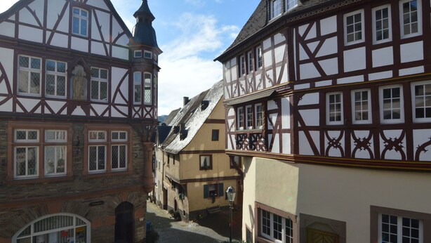 A narrow cobblestone street lined with traditional half-timbered buildings, featuring steep gabled roofs and a prominent tower. - Classy Holiday Home in Rzig near Forest (Uerzig)