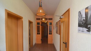 A hallway with wooden doors, a tiled floor, and a hanging light fixture. - Classy Holiday Home in Rzig near Forest (Uerzig)