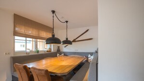 Ein Essbereich mit einem Holztisch, gepolsterten Sitzbänken und Pendelleuchten.