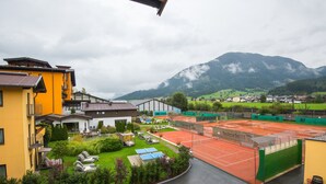 Ein Tennisplatz, umgeben von Gebäuden, mit einem Berg im Hintergrund.