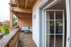 A wooden deck with a sofa and a table, a glass door leading inside, and a view of the outdoors. - Modern Apartment Near the ski Area (Brixen im Thale)