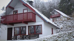 Ein zweistöckiges Gebäude mit einem roten Balkon, großen Fenstern und einem mit Schnee bedeckten Dach.