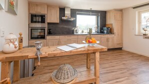 A modern kitchen with wooden cabinets, a stainless steel oven, and a large window. - Ferienhaus in Amelgatzen mit Terrasse (Emmerthal)