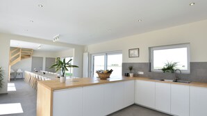 A modern kitchen with a wooden island, white cabinetry, and large windows. - Mansion in Roesbrugge With Garden (Poperinge)