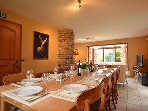 A dining area with a long table set for a meal, a television, and a brick wall. - Nice Holiday Farmhouse Located in Sourbrodt near Ski Resort of Ovifat (Waimes)