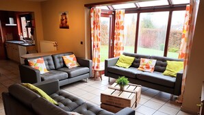 A living room with two sofas, a coffee table, and a view of a garden through large windows. - Nice Holiday Farmhouse Located in Sourbrodt near Ski Resort of Ovifat (Waimes)
