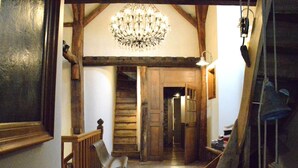 Eine Holztreppe mit einem Chandelier, einem Stuhl und einem Holengeländer.