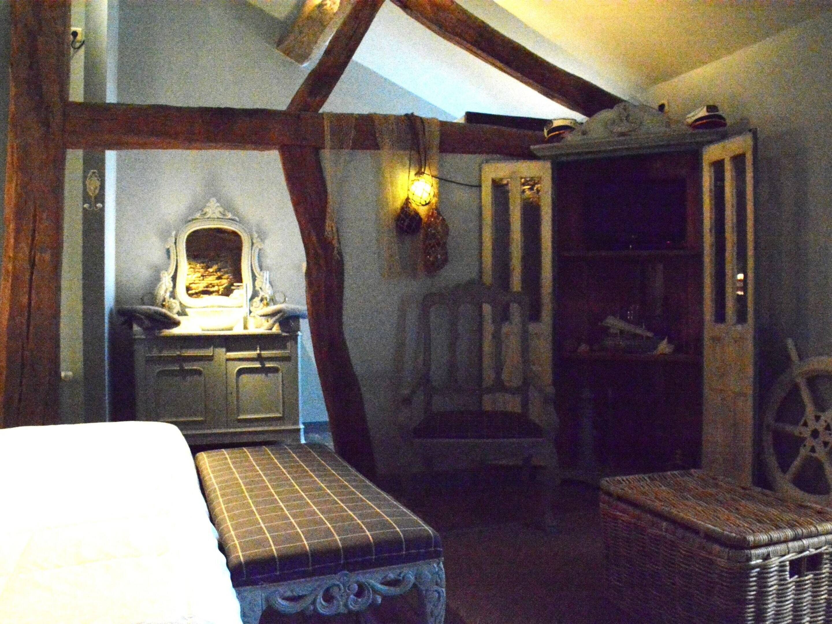 A room with a bed, a dresser, a chair, a small table, and a wall-mounted light fixture.