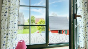 A room with a large window, a wooden floor, and a red wall. - Spacious Holiday Home in Landstorf Zierow near Beach (Zierow)