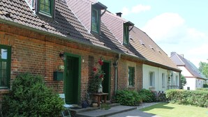 A traditional brick house with a tiled roof, green shutters, and a small front porch with potted plants. - Spacious Holiday Home in Landstorf Zierow near Beach (Zierow)