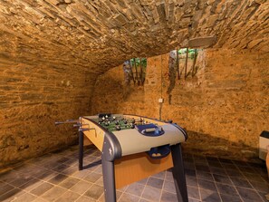 A foosball table in a room with stone walls and tiled floor.