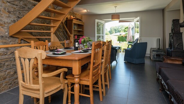 A dining area with a wooden table and chairs, a staircase, and a view of the outdoors. - Sprimont Sauna & Garden Stay (Sprimont)