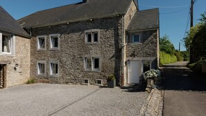A stone building with a gravel driveway and a narrow road. - Sprimont Sauna & Garden Stay (Sprimont)