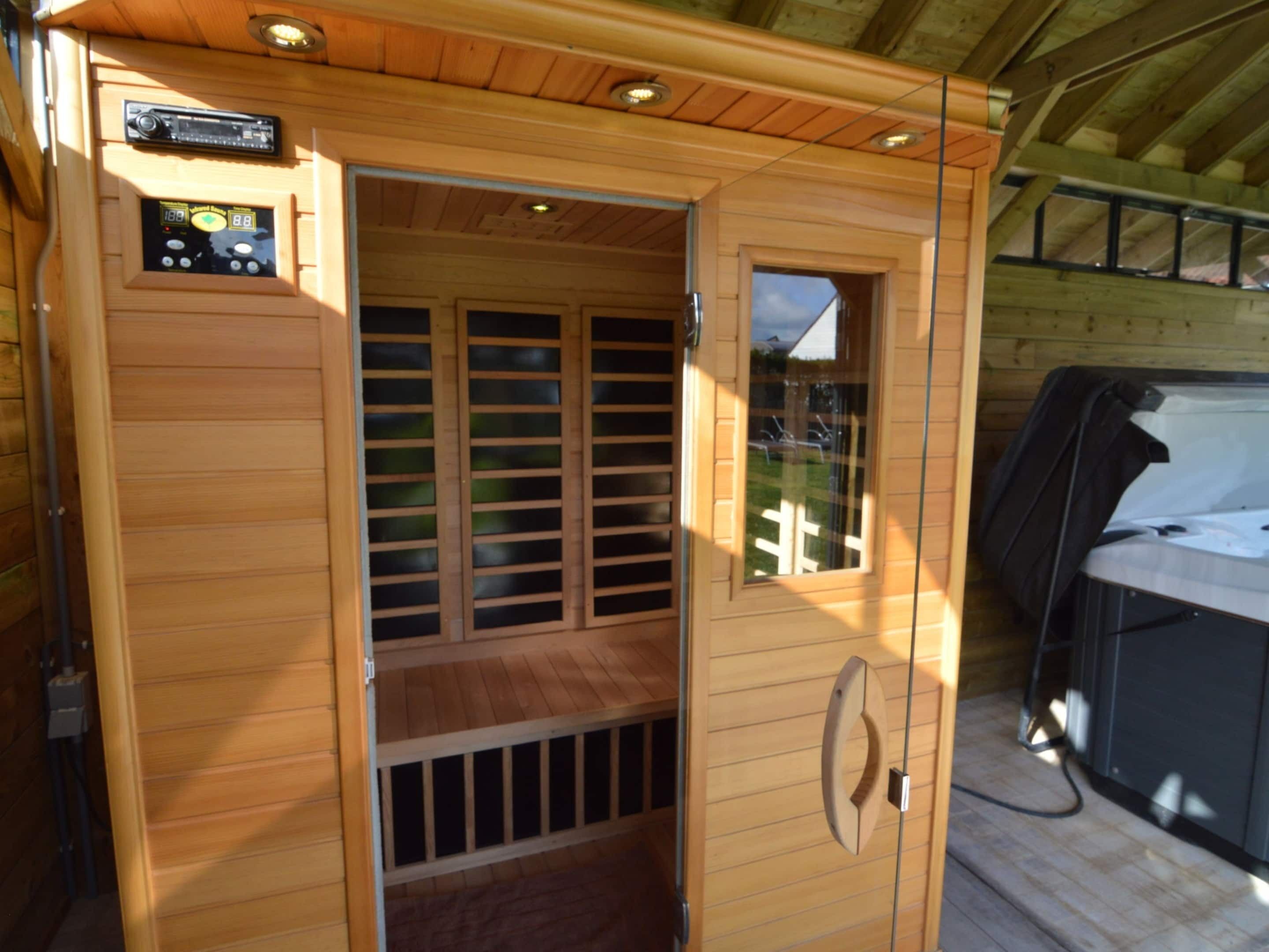 A sauna room with wooden walls, a control panel, and a window.