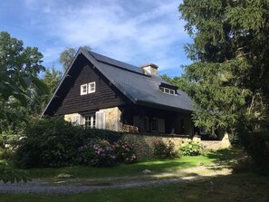 Ein traditionelles Haus mit steilem Dach, Steinmauerwerk und einer kleinen Veranda.