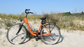 An orange bicycle parked on a sandy beach with sparse vegetation in the background. - Lovely Apartment in Rerik With Private Garden (Rerik)