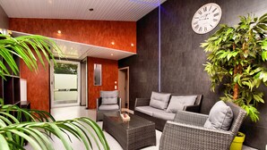 A modern living room with wicker furniture, a coffee table, and a large potted plant. - Modern Family Home With Wellness (La Roche-en-Ardenne)