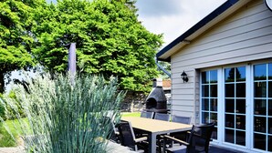 An outdoor patio area with a stone fireplace, a dining table, and chairs. - Modern Family Home With Wellness (La Roche-en-Ardenne)