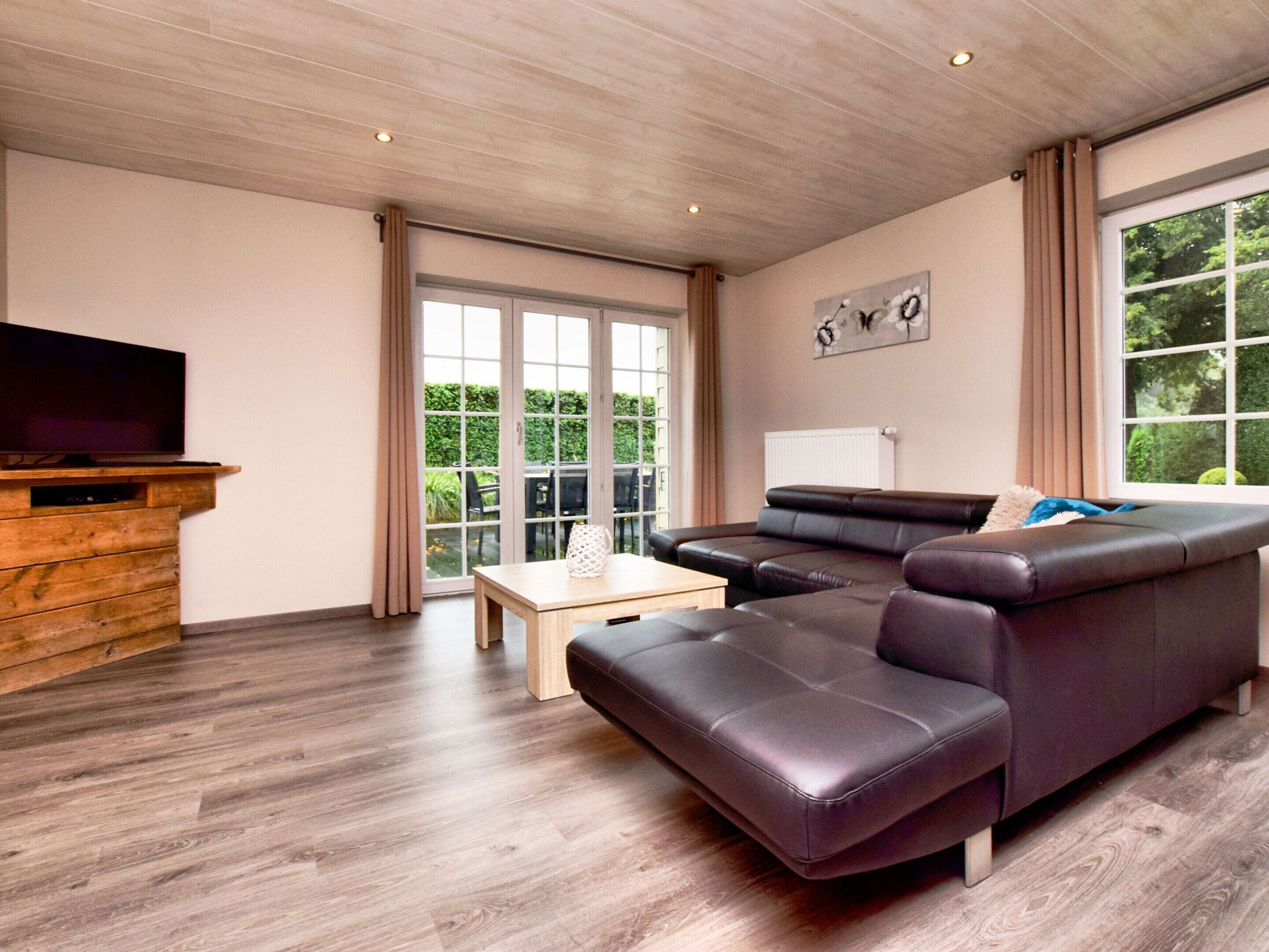 A modern living room with a large sectional sofa, a wooden entertainment unit, and a television.